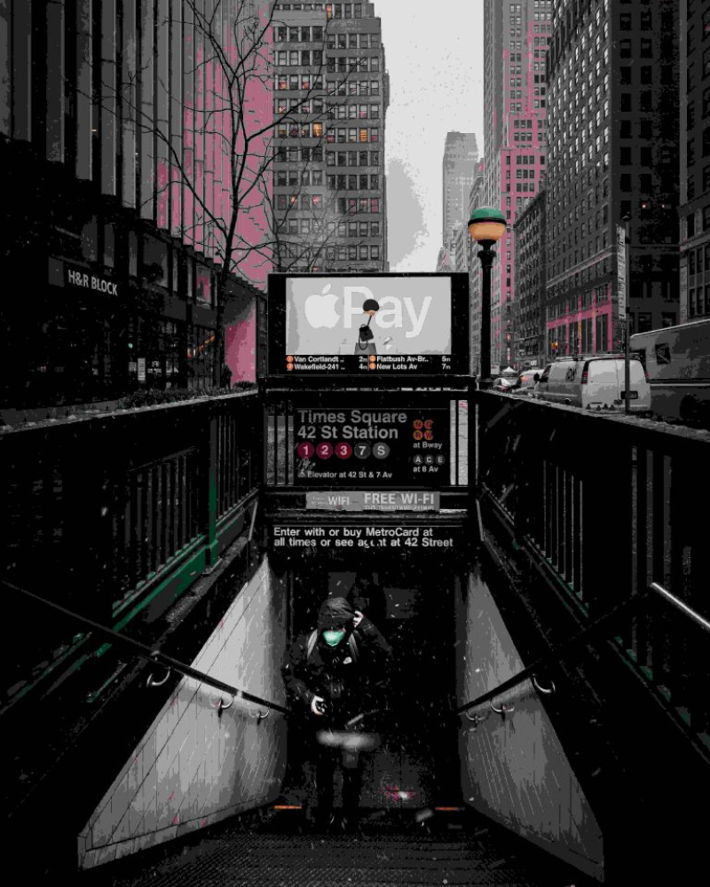 Person descending into subway entrance at Times Square, surrounded by tall buildings and city traffic.