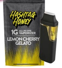 A vape device sits beside packaging labeled Lemon Cherry Gelato 1G All-In-One Vaporizer, blending sweet and tangy flavors in a sleek design.