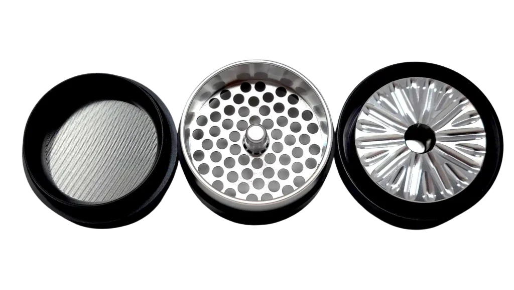 Three parts of a Flower Mill Grinder separated, showing mesh screen, grinding teeth, and holes for filtering.